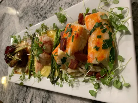 A trio of appetizers with fresh herbs arranged on a long white platter.