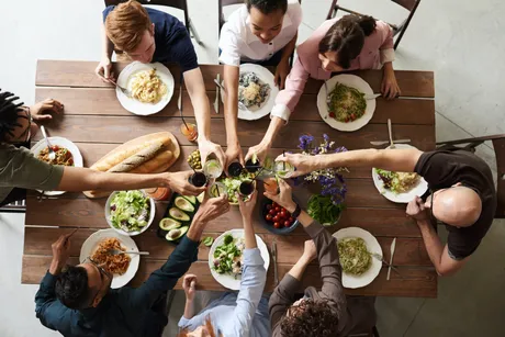 Dinner guests raise their glasses around a table of individually plated meals.