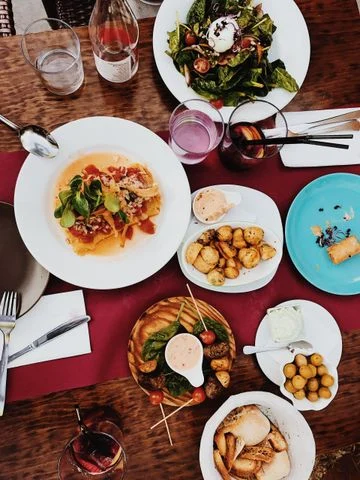Serving dishes of vegetables, bread and entrees arranged for a shared family-style meal.