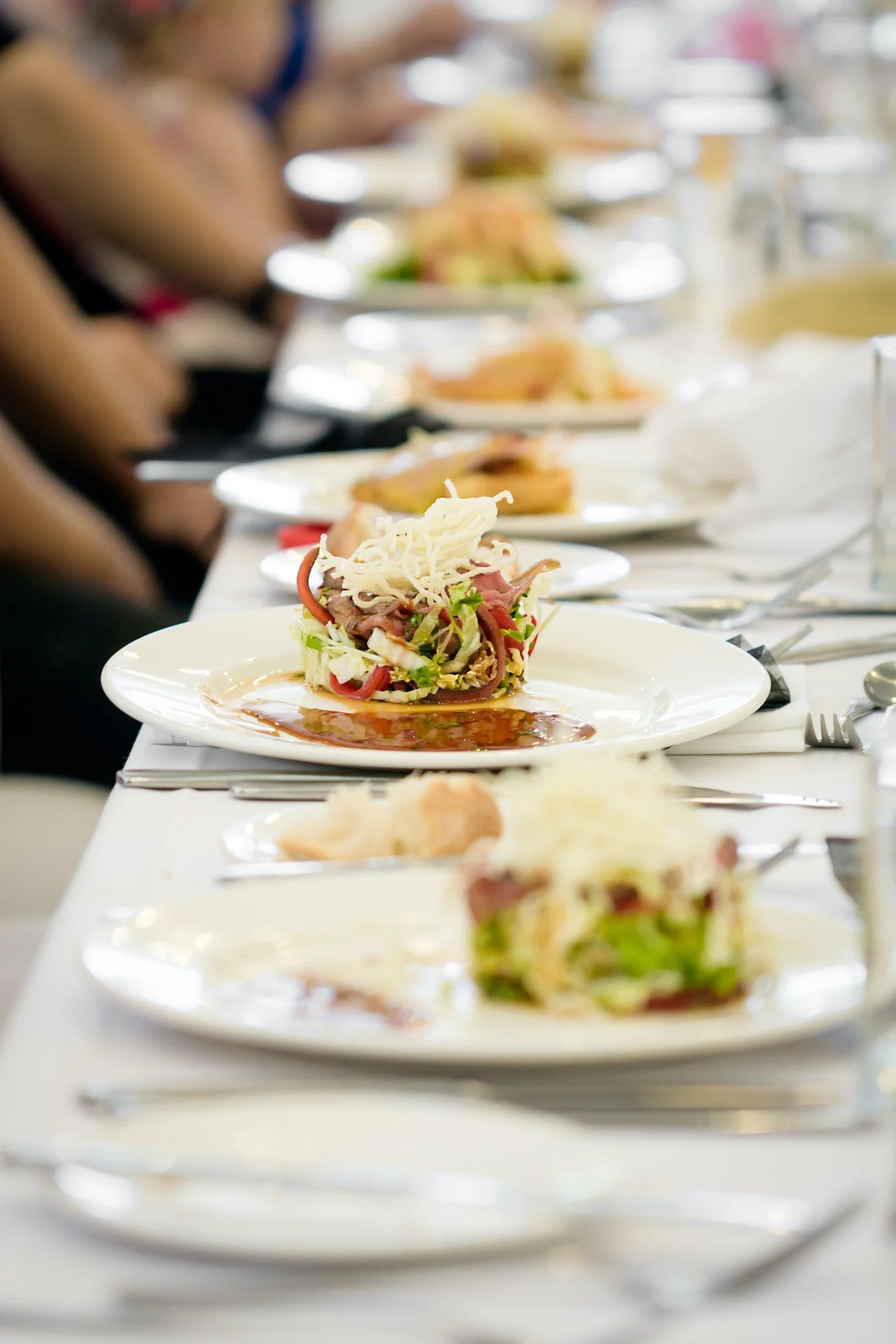 Individually plated courses arranged along a formal dining table.
