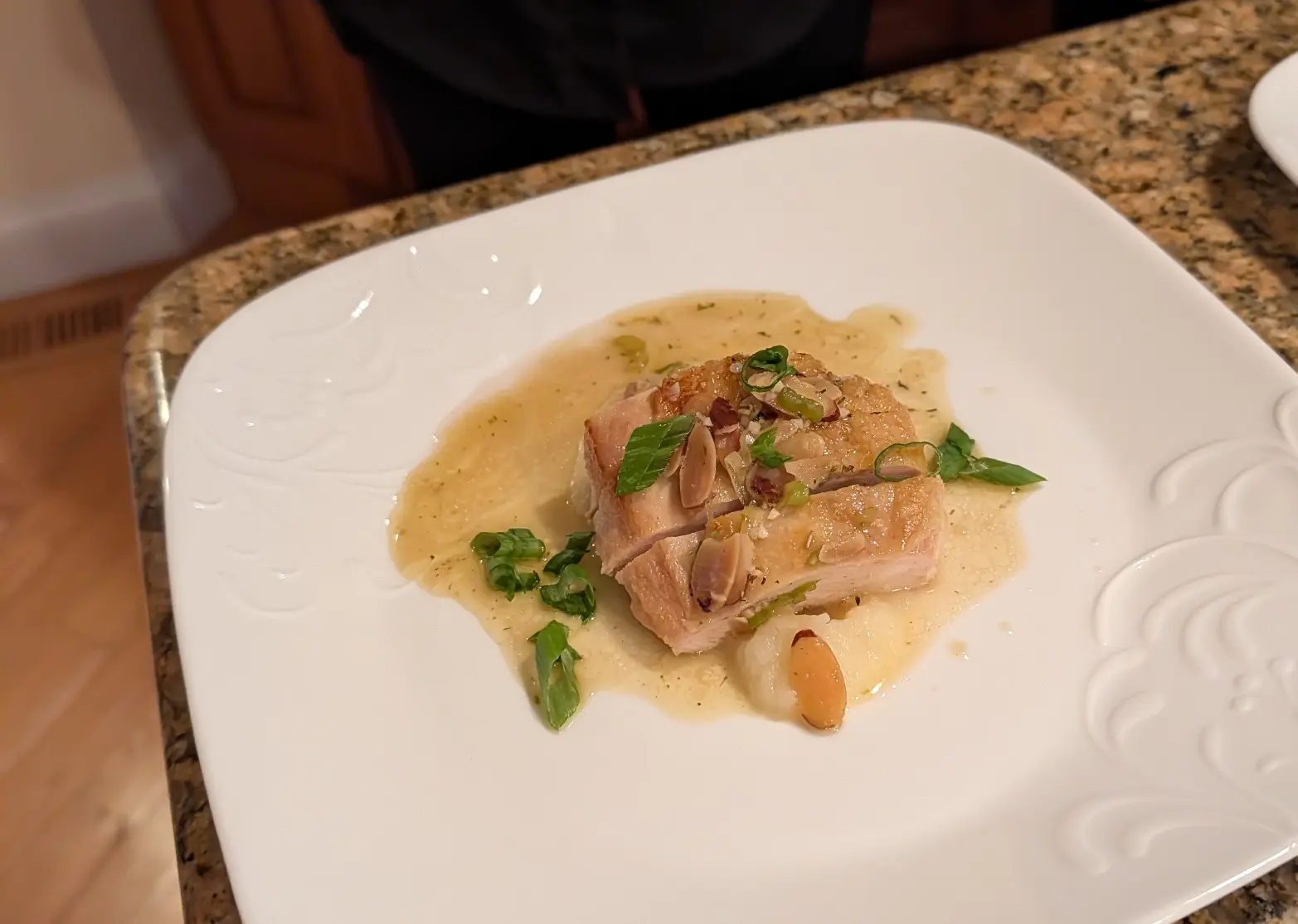 Chicken almondine topped with sliced almonds and herbs in a creamy sauce.