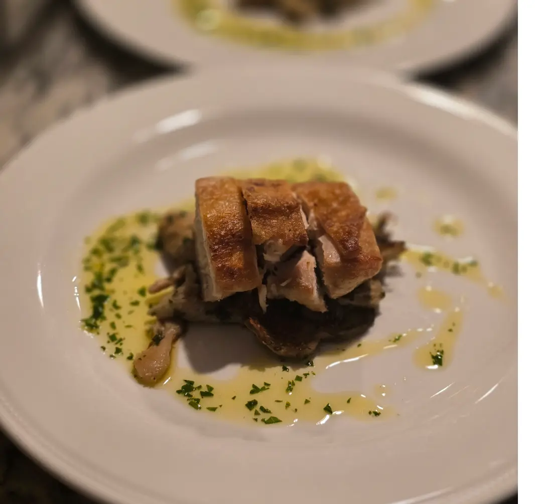 Crispy chicken pieces stacked over vegetables with parsley butter.