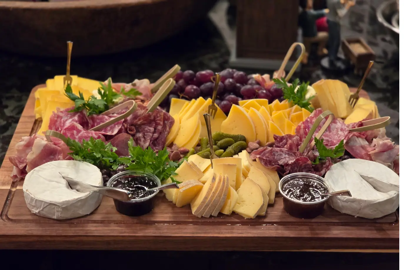A charcuterie board filled with cured meats, cheeses, grapes, crackers and preserves.