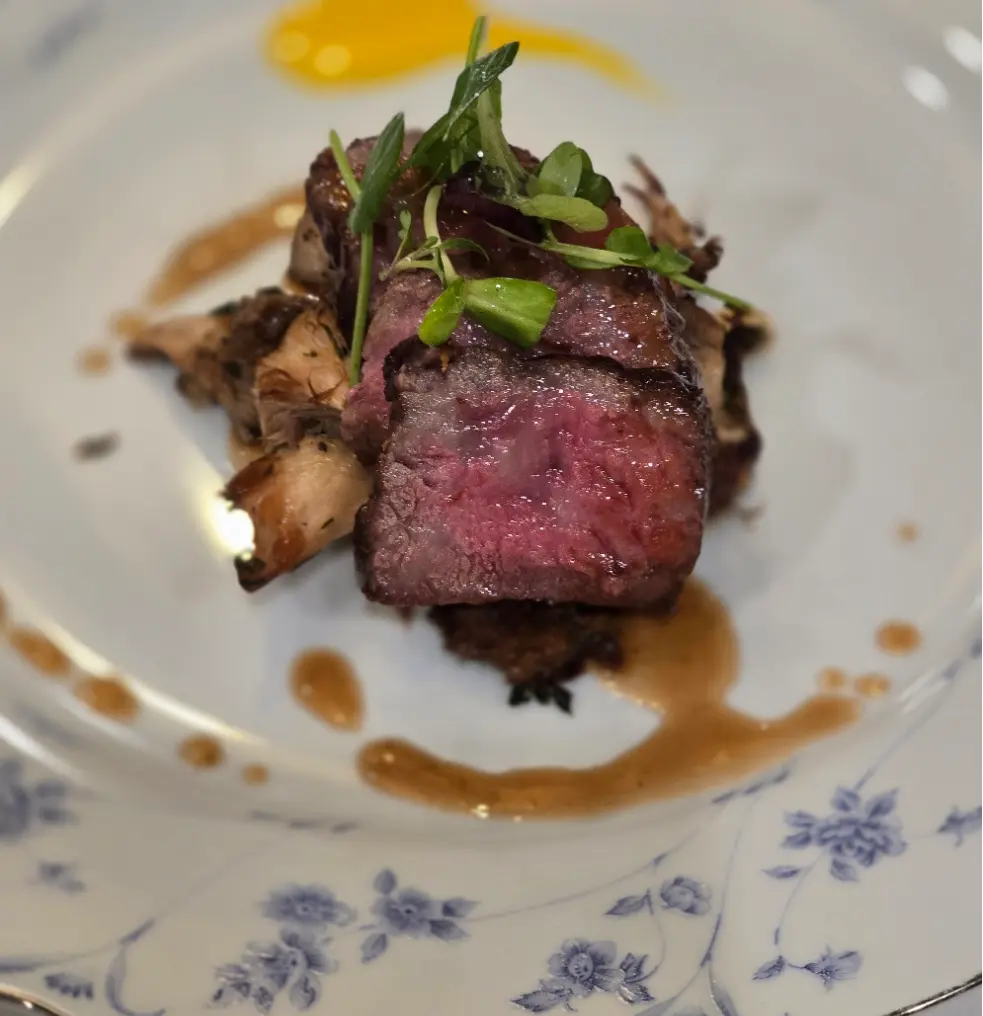 A5 Wagyu beef with mushrooms, microgreens and a glossy brown sauce.