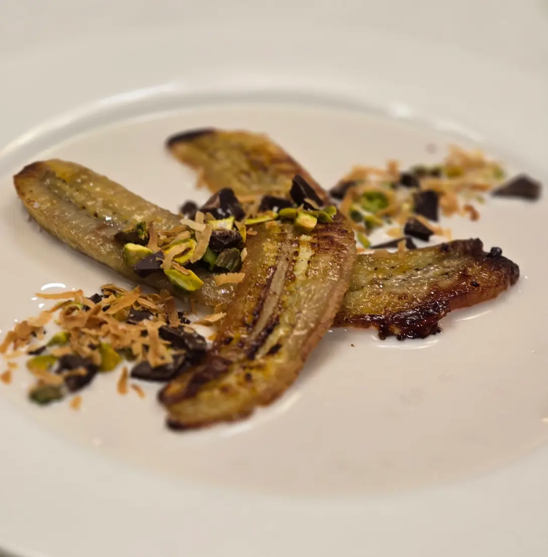 Roasted banana halves with a crumb topping and creamy garnish.