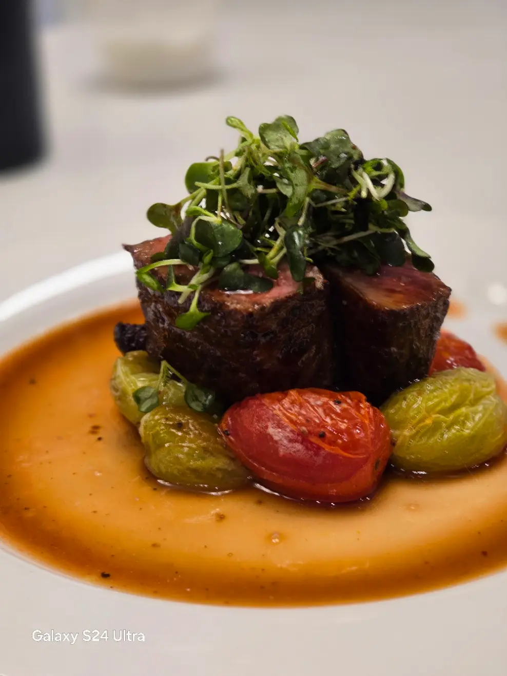 Beef medallions with roasted tomatoes, green vegetables and an orange sauce.
