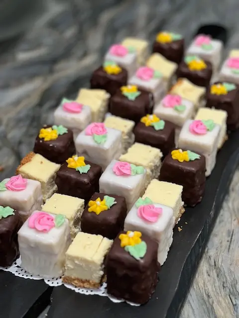 Bite-size chocolate and white-frosted cakes decorated with colorful flowers.