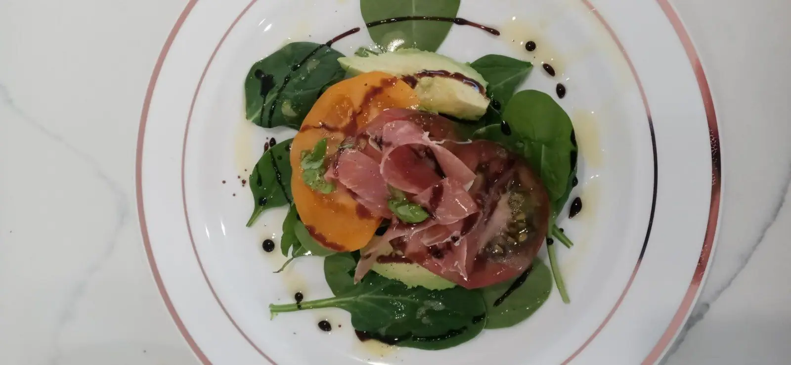 Heirloom tomato slices with leafy greens, pickled onion and a balsamic drizzle.
