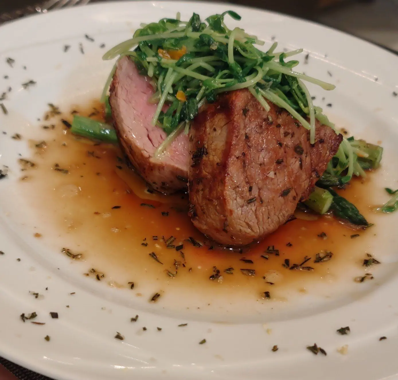 Berkshire pork medallions with microgreens and herb-flecked sauce.