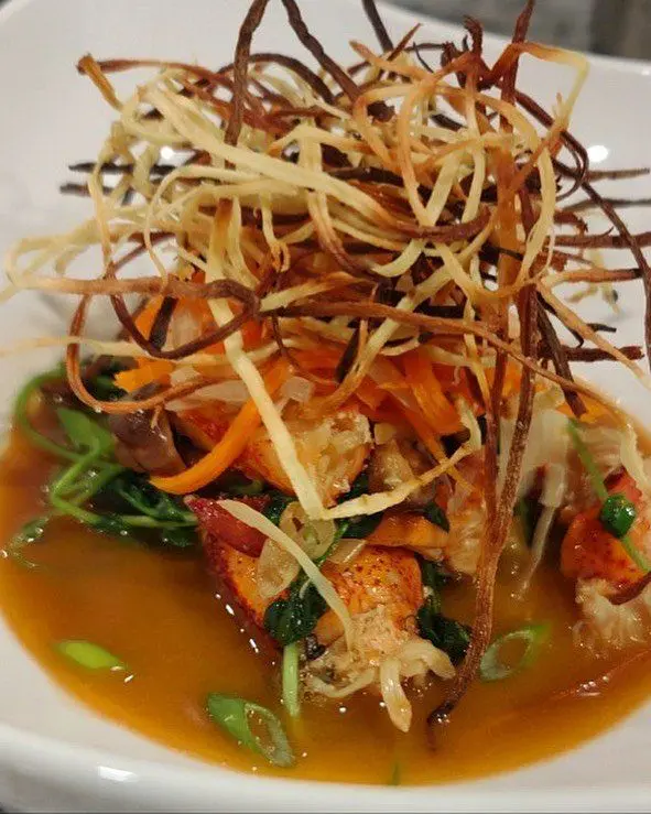 Sauteed lobster and vegetables beneath a tall nest of crisp vegetable strips.