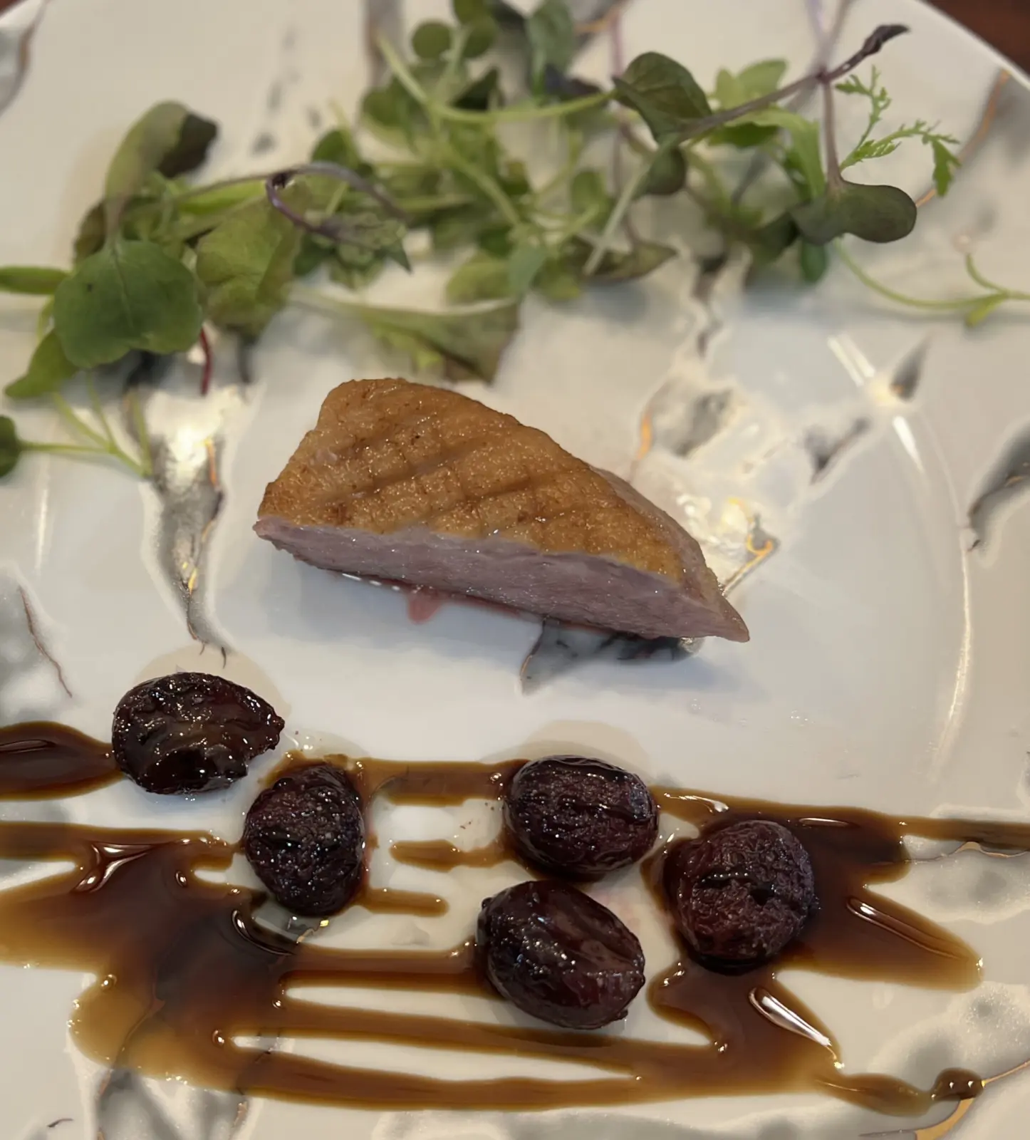 Tapas-style Peking duck with greens, dark sauce and small round garnishes.