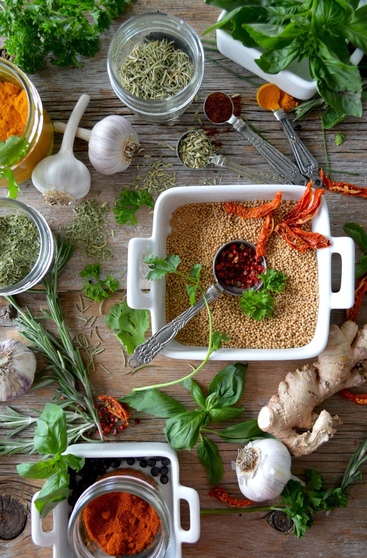 Fresh herbs, garlic, spices and olive oil arranged on a kitchen work surface.