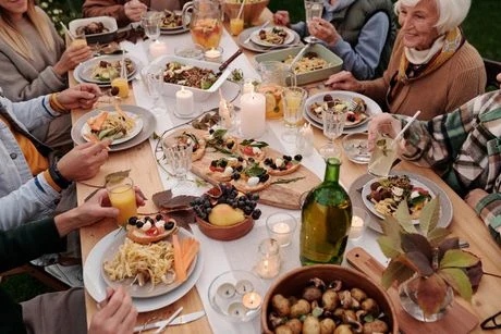 Friends gathered around a dinner table with wine, shared dishes and plated meals.