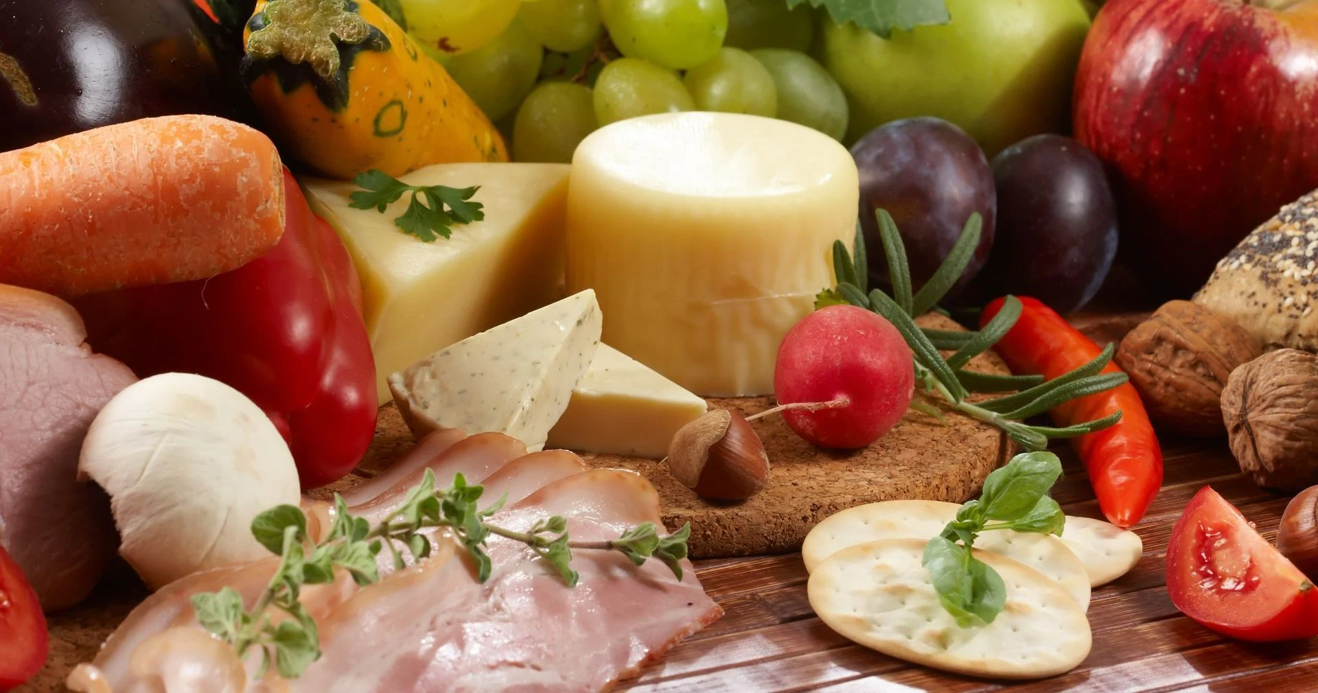 An assortment of fresh produce, cheeses, nuts, bread and cured meats.